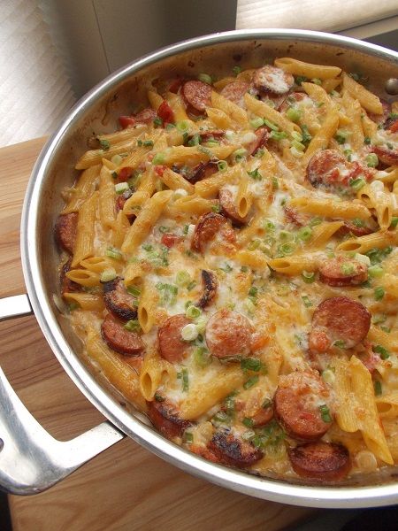 a pan filled with pasta and sausage on top of a wooden table