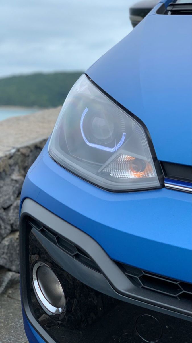 the front end of a blue car with its lights on