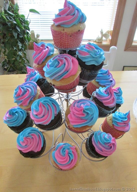 cupcakes with blue and pink frosting are arranged on a wire stand