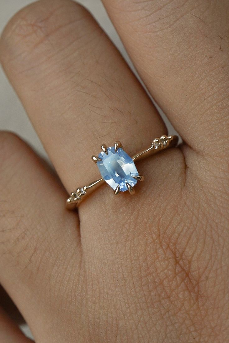 a woman's hand with a ring on it and a blue stone in the middle