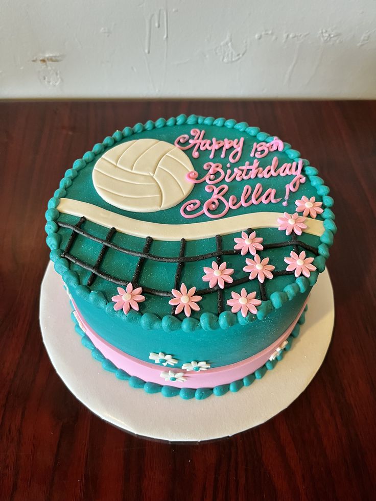 a birthday cake decorated with flowers and a volleyball ball on the top is sitting on a table