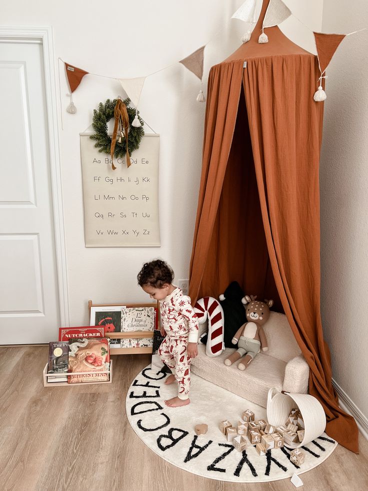 a small child is playing with toys in his bedroom and on the floor next to a teepee tent