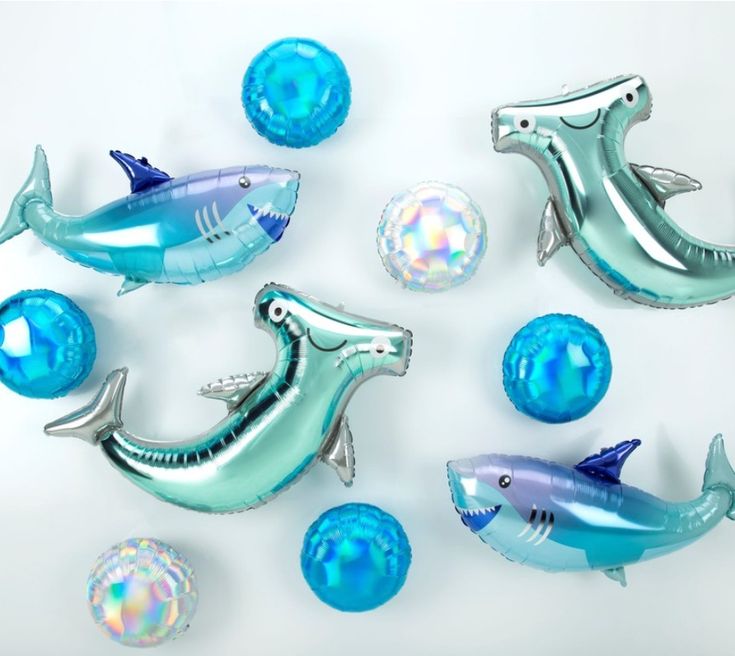 some blue and silver foiled balloons are in the shape of dolphins, fish, and bubbles