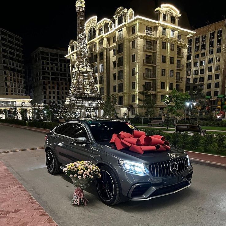 a car parked in front of a building with red bows on it's hood