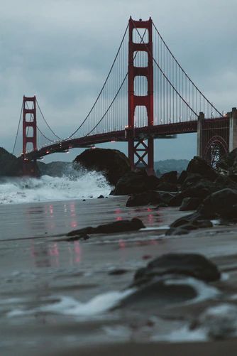 the golden gate bridge in san francisco is lit up with red lights as waves crash on the shore