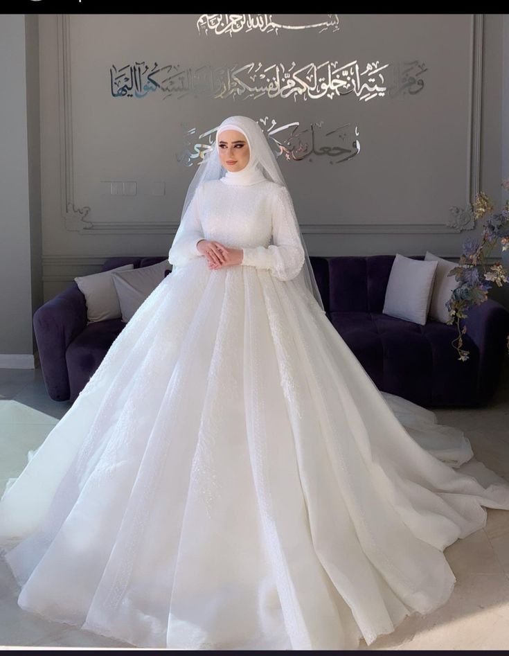 a woman in a white wedding dress standing next to a couch