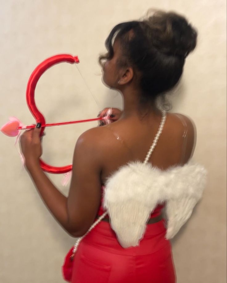 a woman in a red dress is holding a bow and arrow with white feathers on it