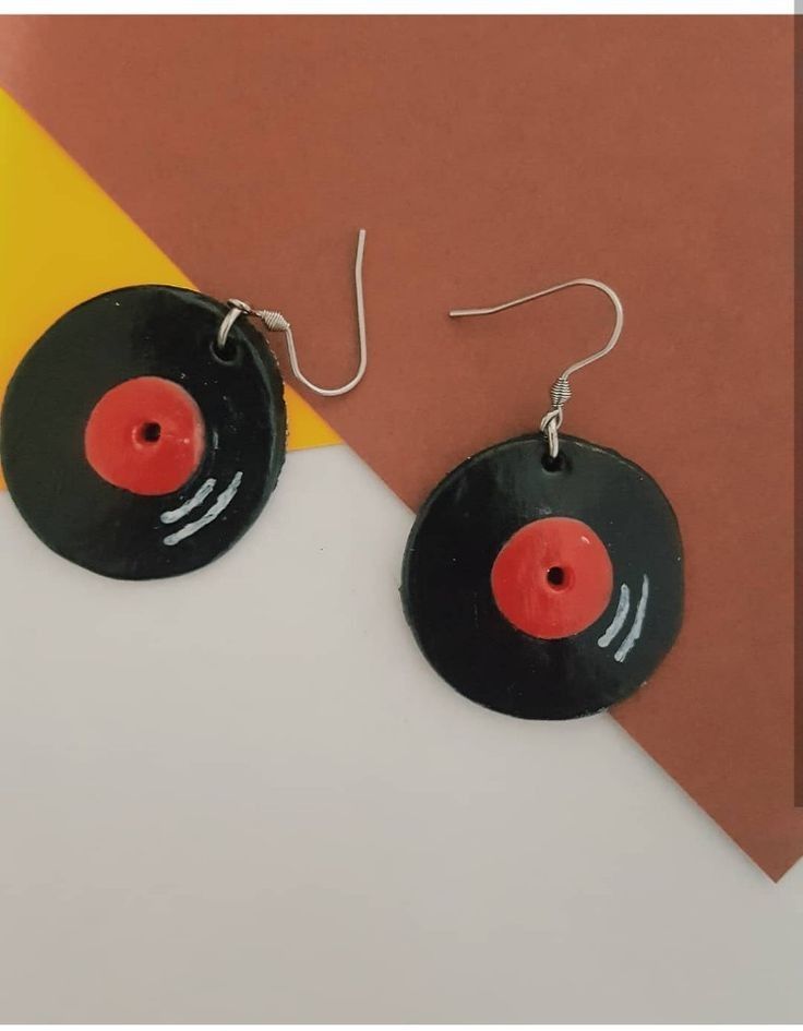 black and red disc shaped earrings with silver earwires on top of a colorful background