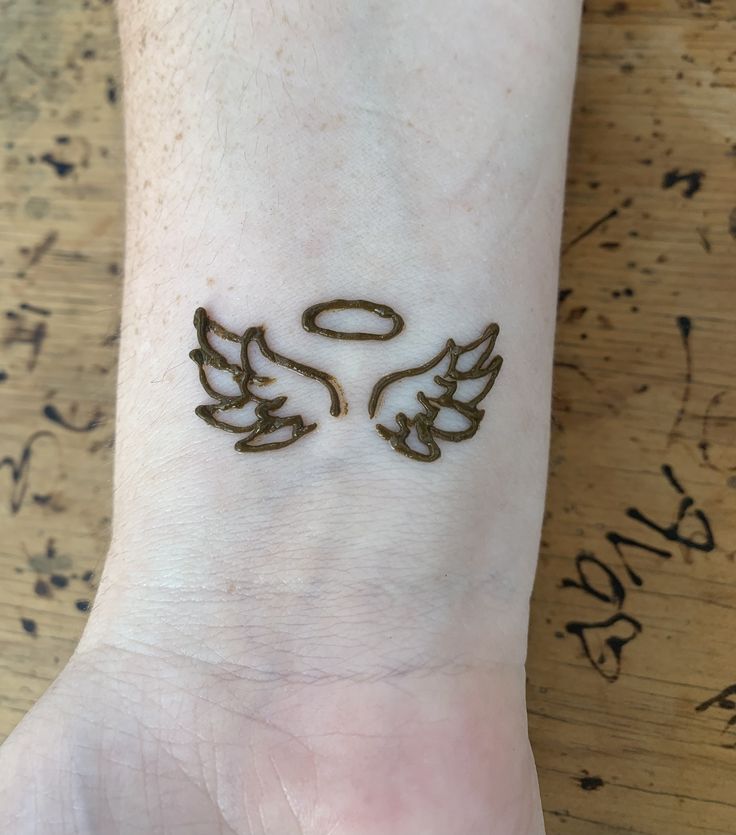 a person with a tattoo on their wrist that has two wings in the shape of an angel