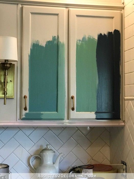 kitchen cabinets with green paint on them and white tile backsplash in the background