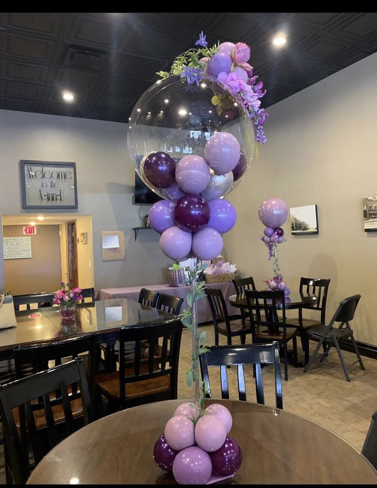 the balloon centerpiece is filled with purple and lilac balloons in a dining room