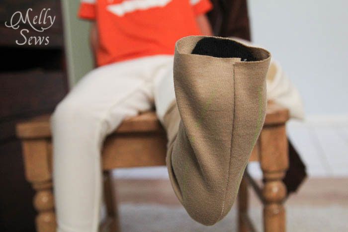 a person sitting on a chair with their foot in a shoe cover that has been made to look like a boot