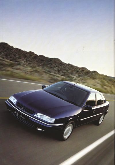 a black car driving down the road with mountains in the backgrounds