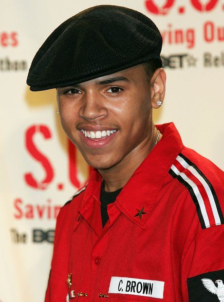 a young man in a red uniform smiles at the camera while wearing a black hat