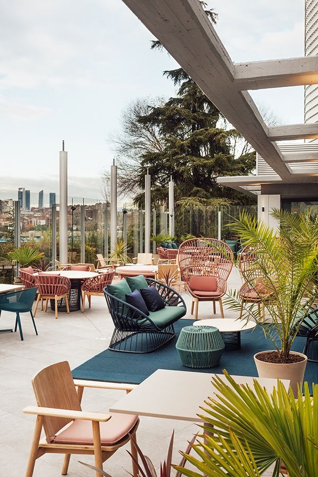 an outdoor seating area with chairs, tables and potted plants on the roof terrace