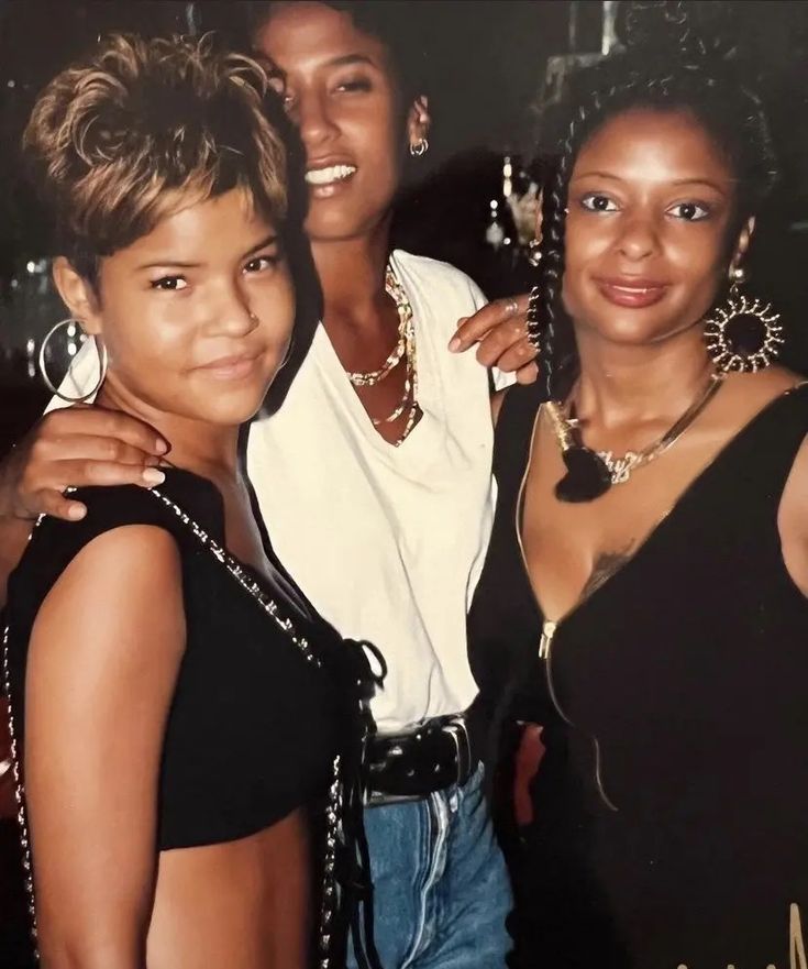 three women posing for the camera with one holding her arm around another woman's shoulder