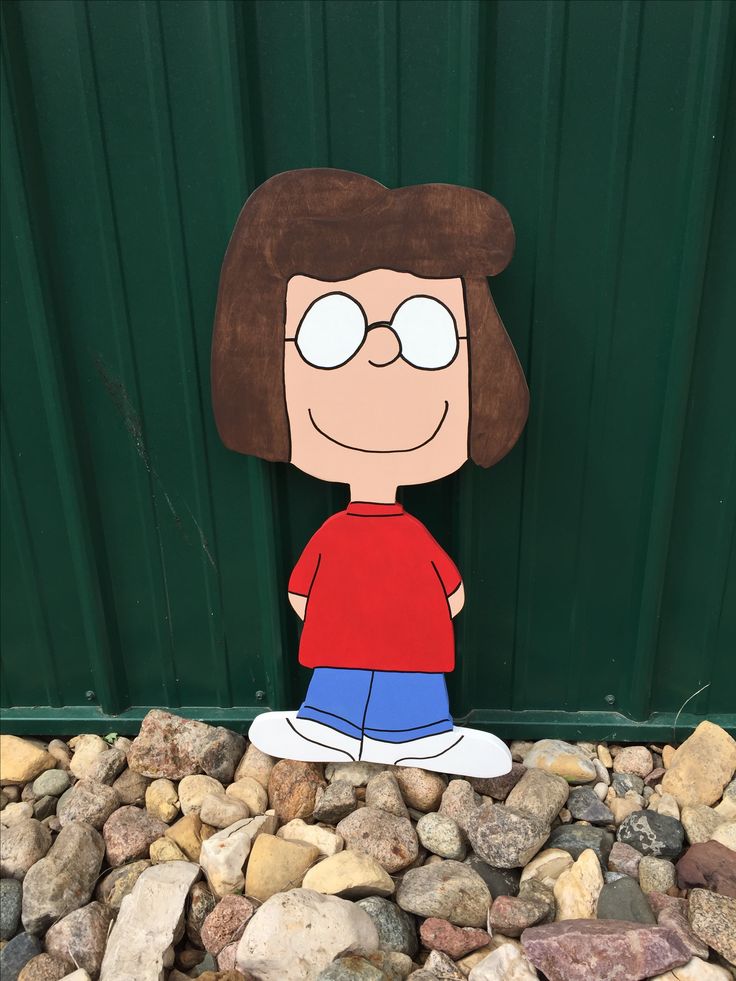 a cardboard cutout of a cartoon character sitting on rocks in front of a green wall