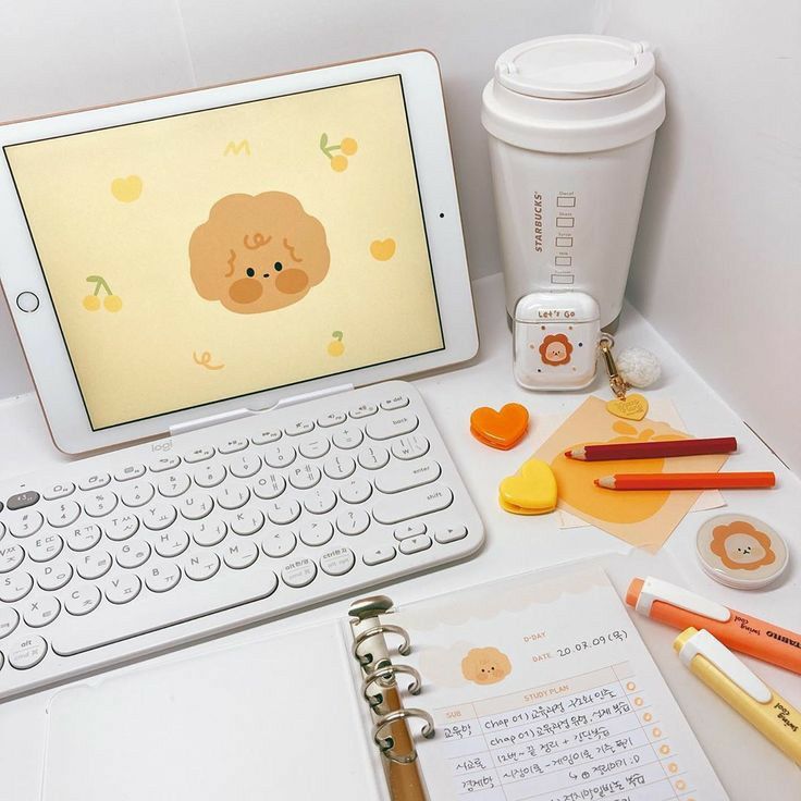 a laptop computer sitting on top of a desk next to a cup and pencils