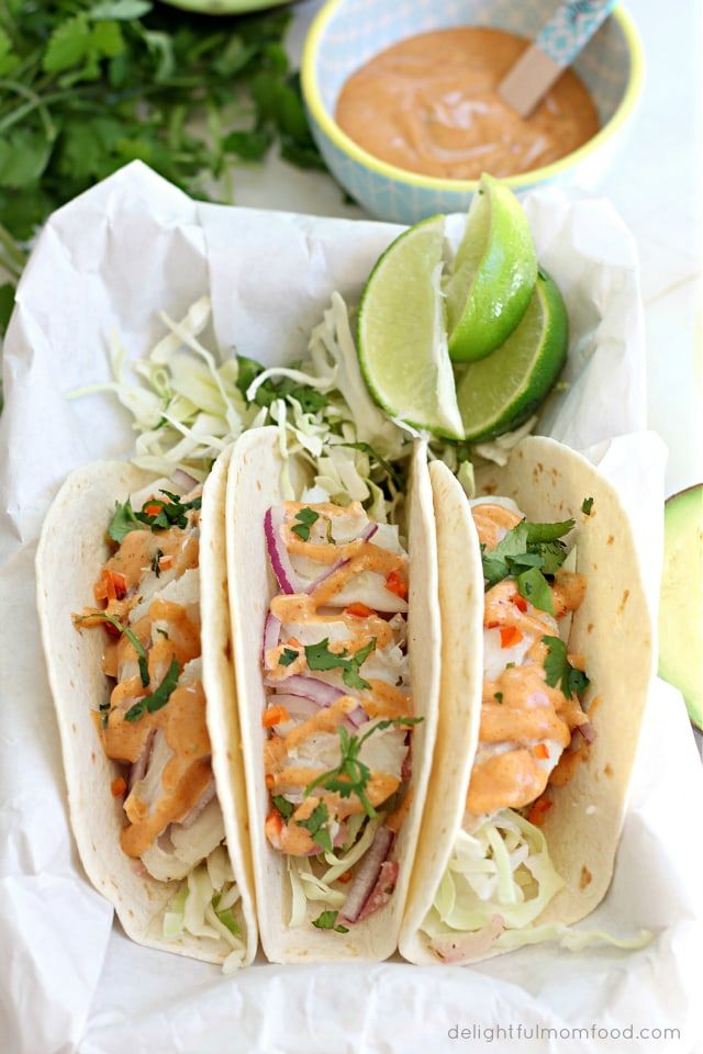 three fish tacos with cole slaw and avocado garnished with cilantro