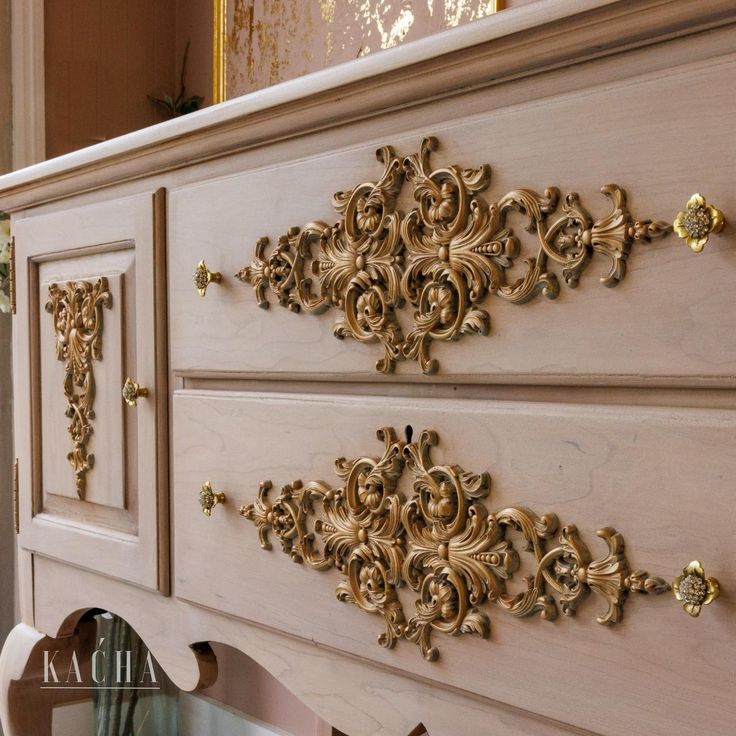 an ornately decorated dresser is shown with gold accents on the doors and drawer pulls