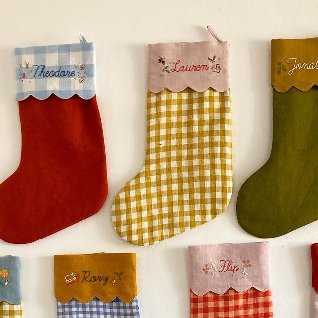 several christmas stockings hanging on the wall with name tags attached to each stocking, all decorated in different colors and designs