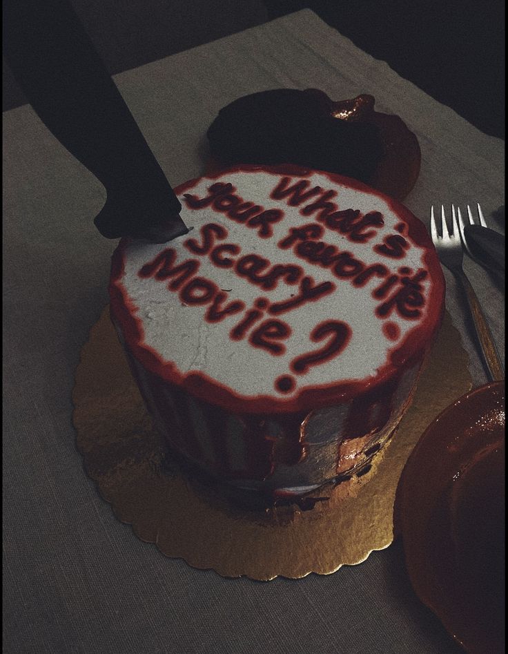 a cake with writing on it sitting on top of a table next to a knife and fork