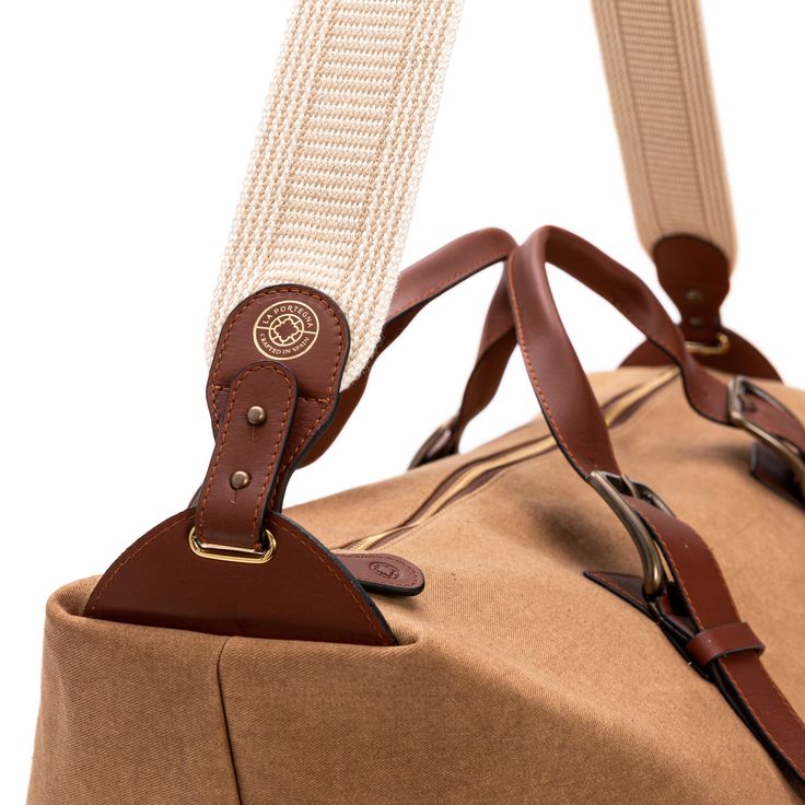 Safari-style light and resistant canvas travel bag.   Zip closure.  Adjustable buckle straps.   Removable and adjustable strap.   Internal pockets.   Material: canvas and vegetable tanned leather.   Available to customize.  Size: Base width 26 cm x Width 65 cm x Height 30 cm x Depth 20 cm.   Light and resistant travel bag made of canvas and leather. Its surprisingly spacious interior contains internal pockets to keep personal items organized. It is a bag designed to take on a weekend getaway or Leather Handle Tote Luggage For Weekend Trips, Classic Travel Accessories With Leather Handles For Daily Use, Brown Coated Canvas Luggage For Overnight Trips, Classic Everyday Travel Accessories With Leather Trim, Duck Canvas Bag With Leather Patch For Everyday Use, Everyday Duck Canvas Bag With Leather Patch, Leather Handle Tote Duffle Bag For Weekend Trips, Weekend Tote Duffle Bag With Leather Handles, Weekend Duffle Bag With Leather Handles