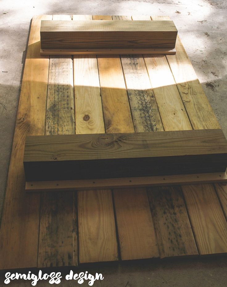 a wooden bench sitting on top of a cement ground next to a tree and grass