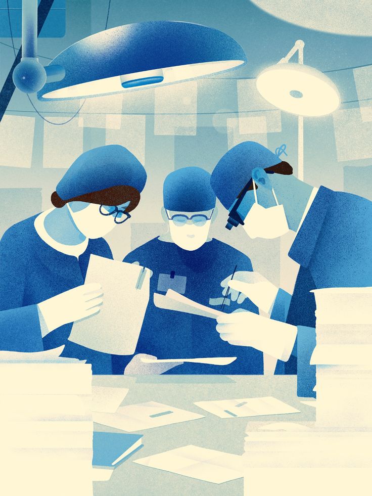 three people in surgical garb are looking at papers on a table with lights above them