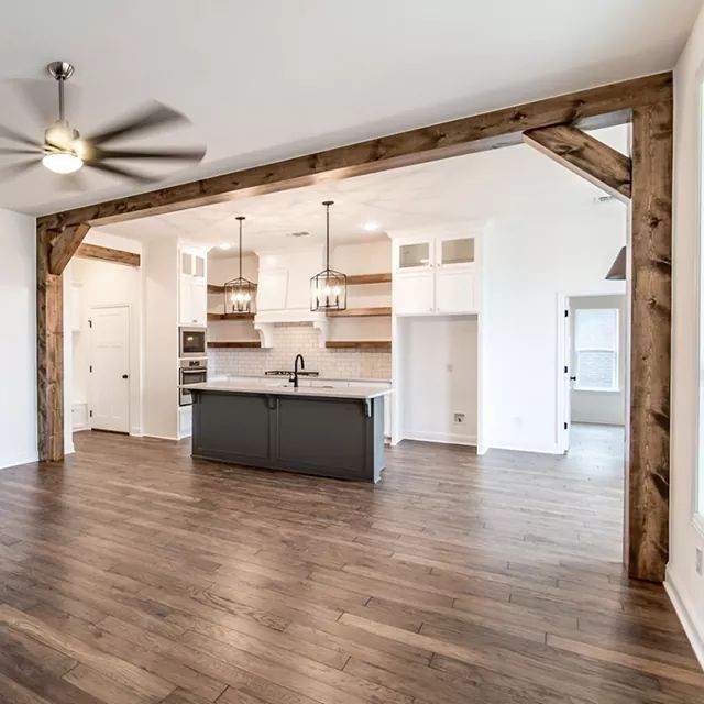 an empty kitchen and living room in a house with wood flooring, white walls and ceiling fan