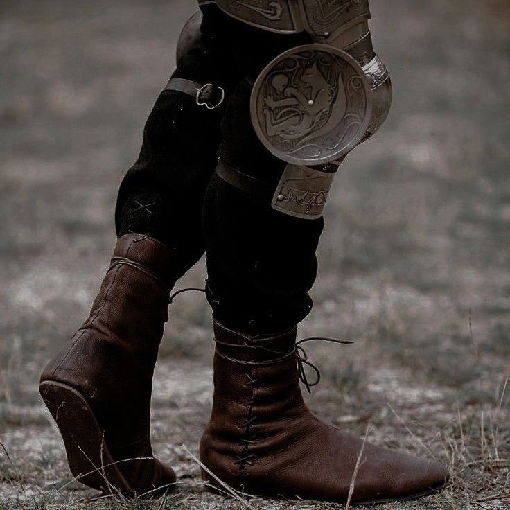 a close up of a person's boots and leg in the grass with an animal on it