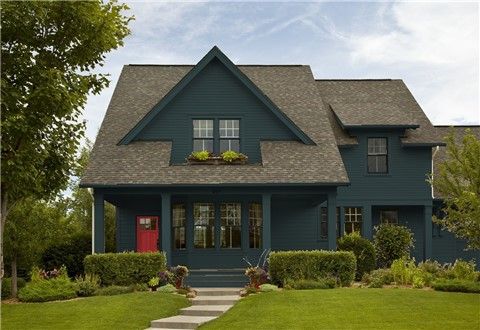 a gray house with black shutters on the front door and green grass in front