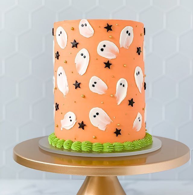 a halloween cake with ghost and stars on the icing is sitting on a gold plate