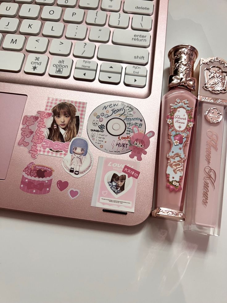 a pink laptop computer sitting on top of a white desk next to a bottle of perfume