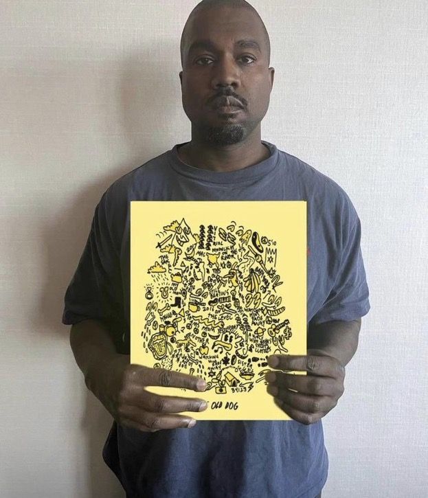 a man holding up a yellow piece of paper with black and white drawings on it