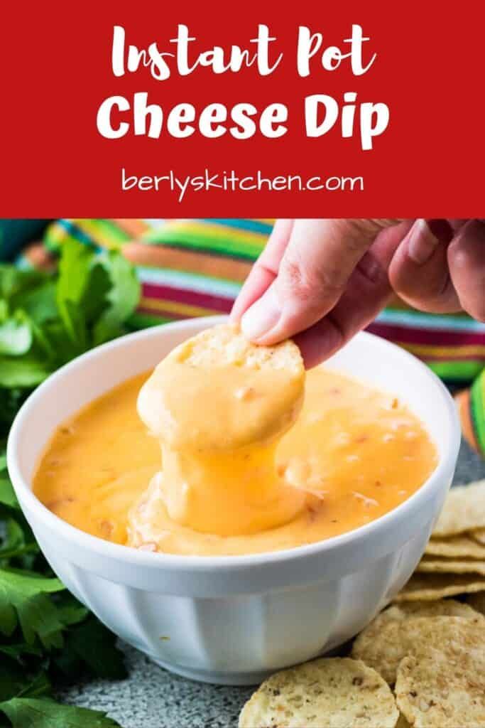 a person dipping cheese into a white bowl with tortilla chips on the side