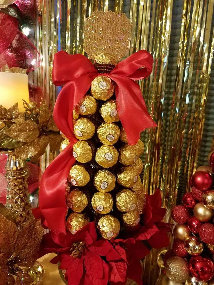 a christmas tree made out of chocolates with red ribbon and gold decorations in the background