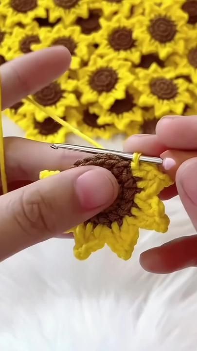 someone is crocheting sunflowers on the table with scissors in their hands