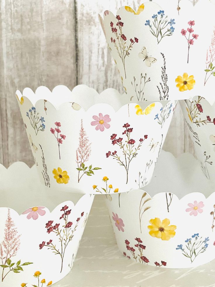 four flowered paper muffin cups sitting on top of a white tablecloth covered surface