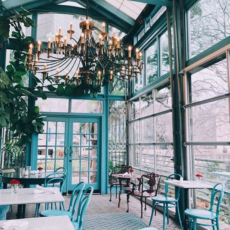 the inside of a restaurant with tables and chairs, chandelier and plants hanging from the ceiling