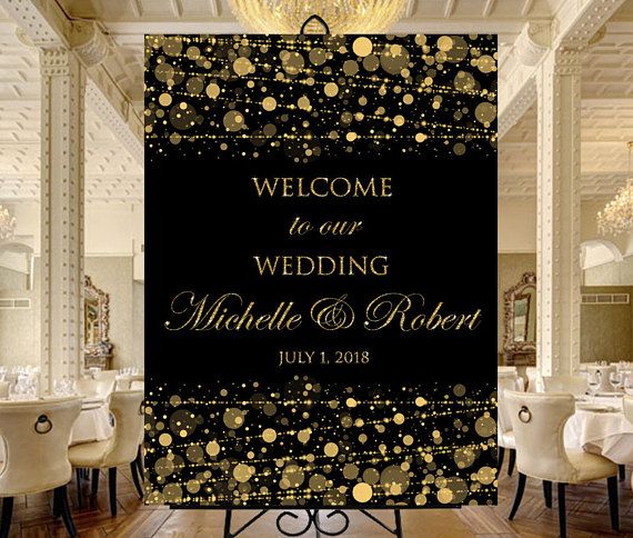 a black and gold wedding welcome sign in front of a banquet table with white chairs