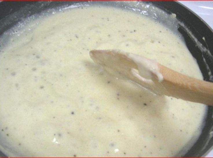 a wooden stick sticking out of a pot filled with cream and cheese sauce on top of a table