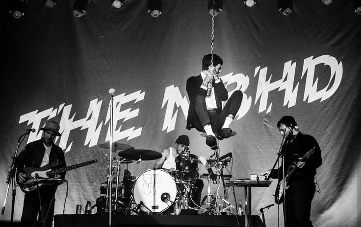 three men are performing on stage with instruments