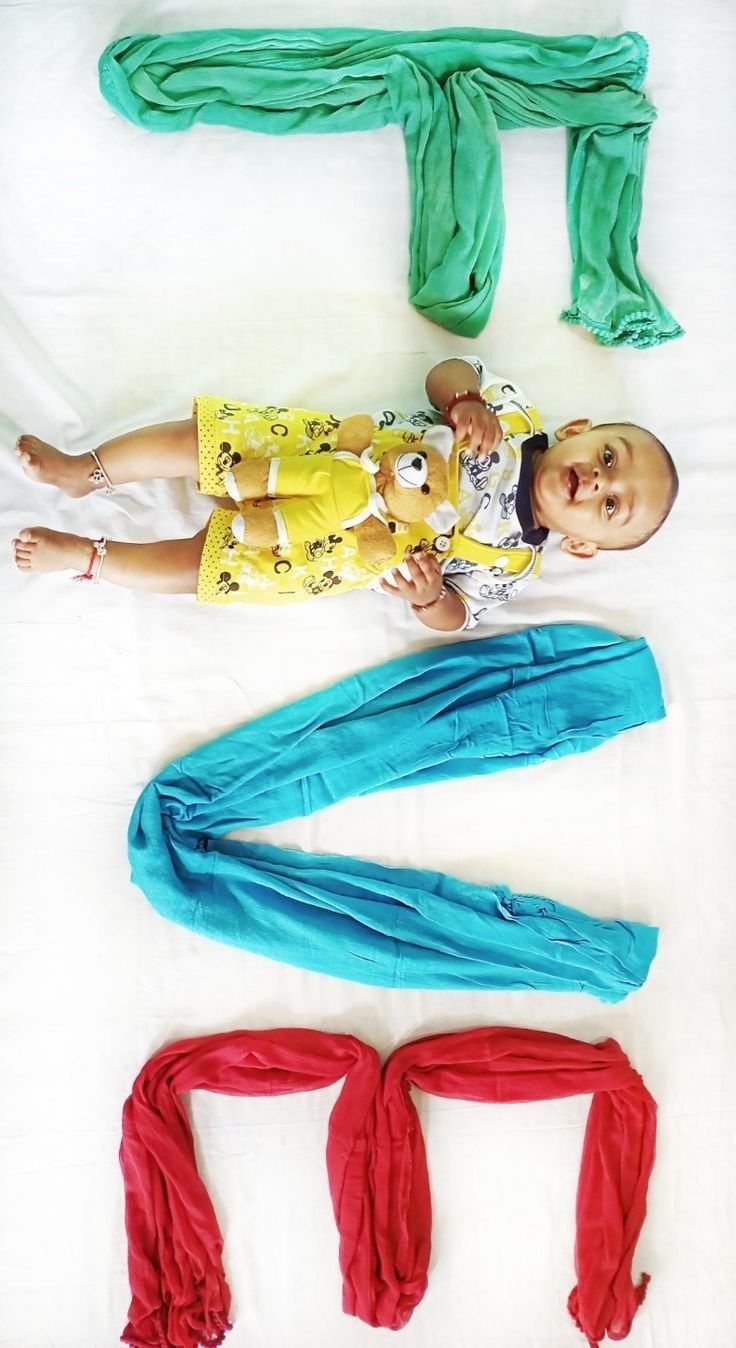 a baby laying on top of a bed next to two scarves and an object