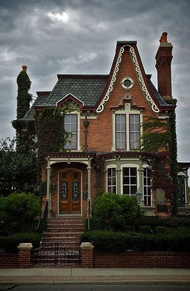 an old brick house with ivy growing on it's roof and stairs leading up to the front door