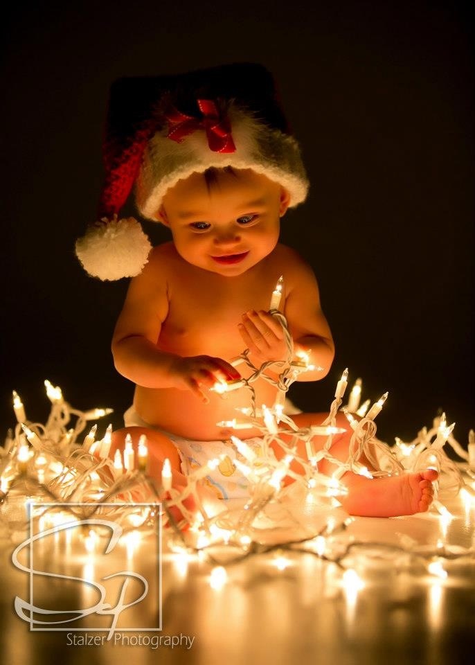 a baby wearing a santa hat sitting on top of a table covered in christmas lights