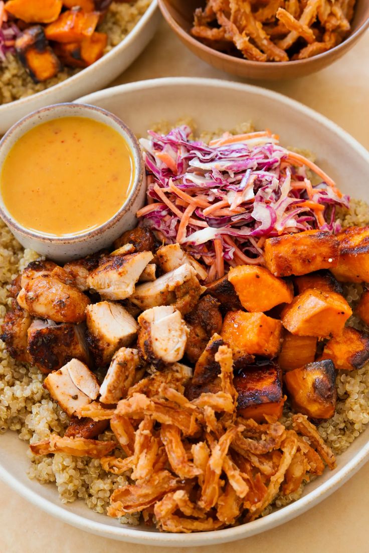 two plates filled with different types of food on top of a table next to bowls of dipping sauce