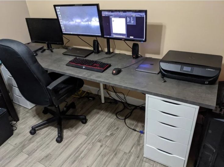 a computer desk with two monitors and a printer