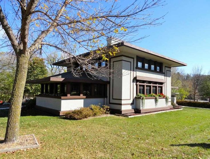 a large house sitting on top of a lush green field next to a tree with lots of leaves