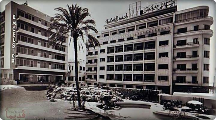 an old black and white photo of a building with palm trees in the foreground